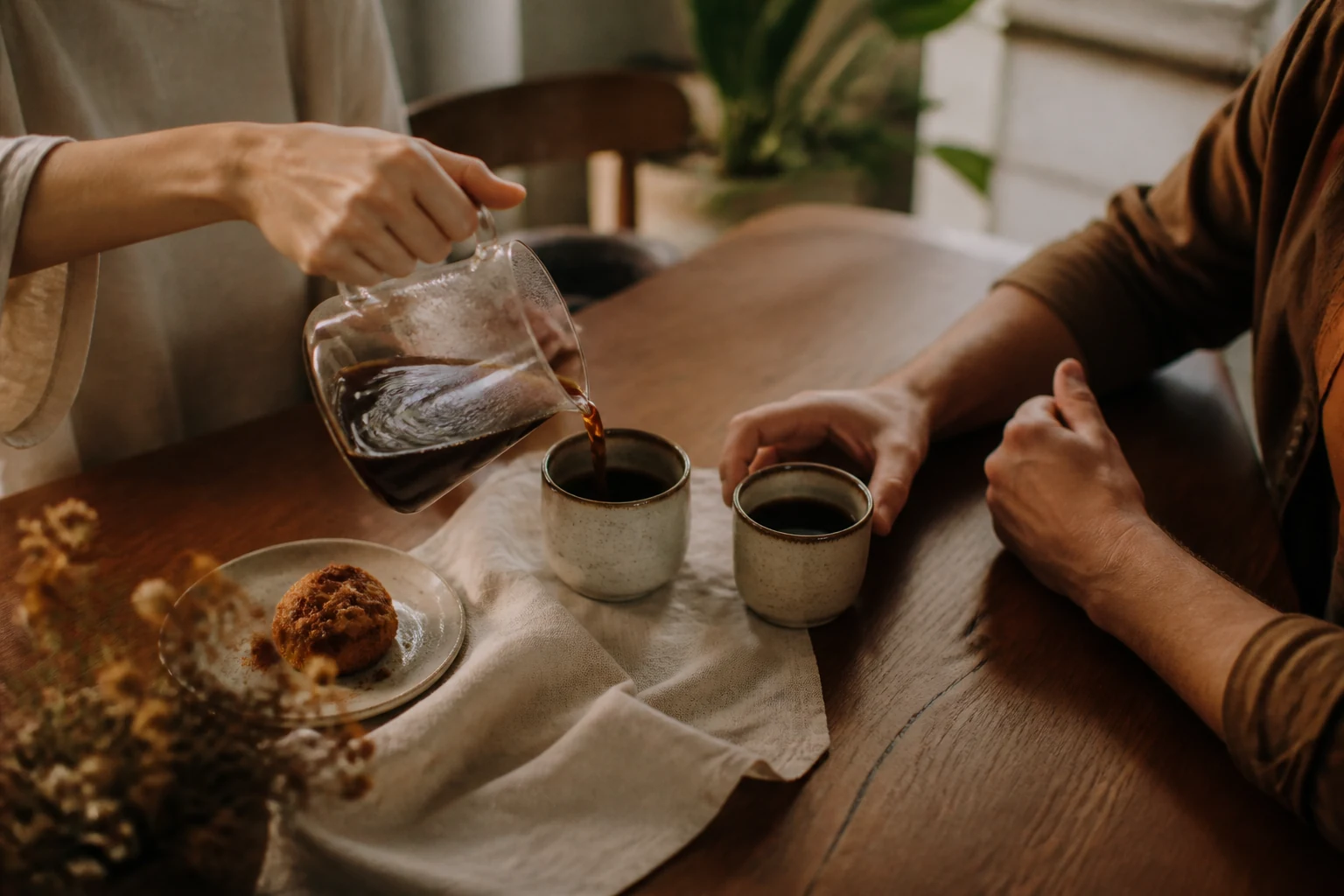 Duas pessoas compartilhando o preparo de café em uma mesa acolhedora